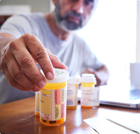 senior hispanic man with beard looking at a collection of medications
