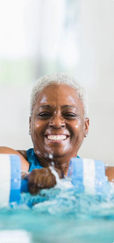 smiling adult woman swimming laps in pool